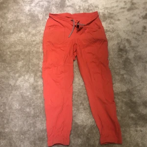 Houdini byxor  - Tunna Houdini byxor i rödaprikos färg för till exempel vandring på sommaren. Jättebra skick, i stort sett aldrig använda av mig då de är för korta. Jag är 170, men passar snarare på någon som är 160-165 cm. 