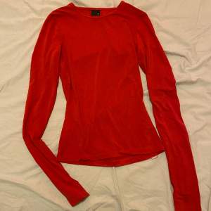 En väldigt röd långärmad tröja i silke som inte kommer till användning 