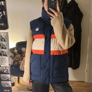 By Malina väst  - Jättevarm, tjock väst från By Malina. Modell: ”Zermatt ski puffer vest”. Nypris 1599kr. Aldrig använd, lappen kvar. En defekt finns, knappen längst upp är trasig (bild 3). Den var så när jag köpte den (aldrig använd), men går att lösa. Fler bilder finns!