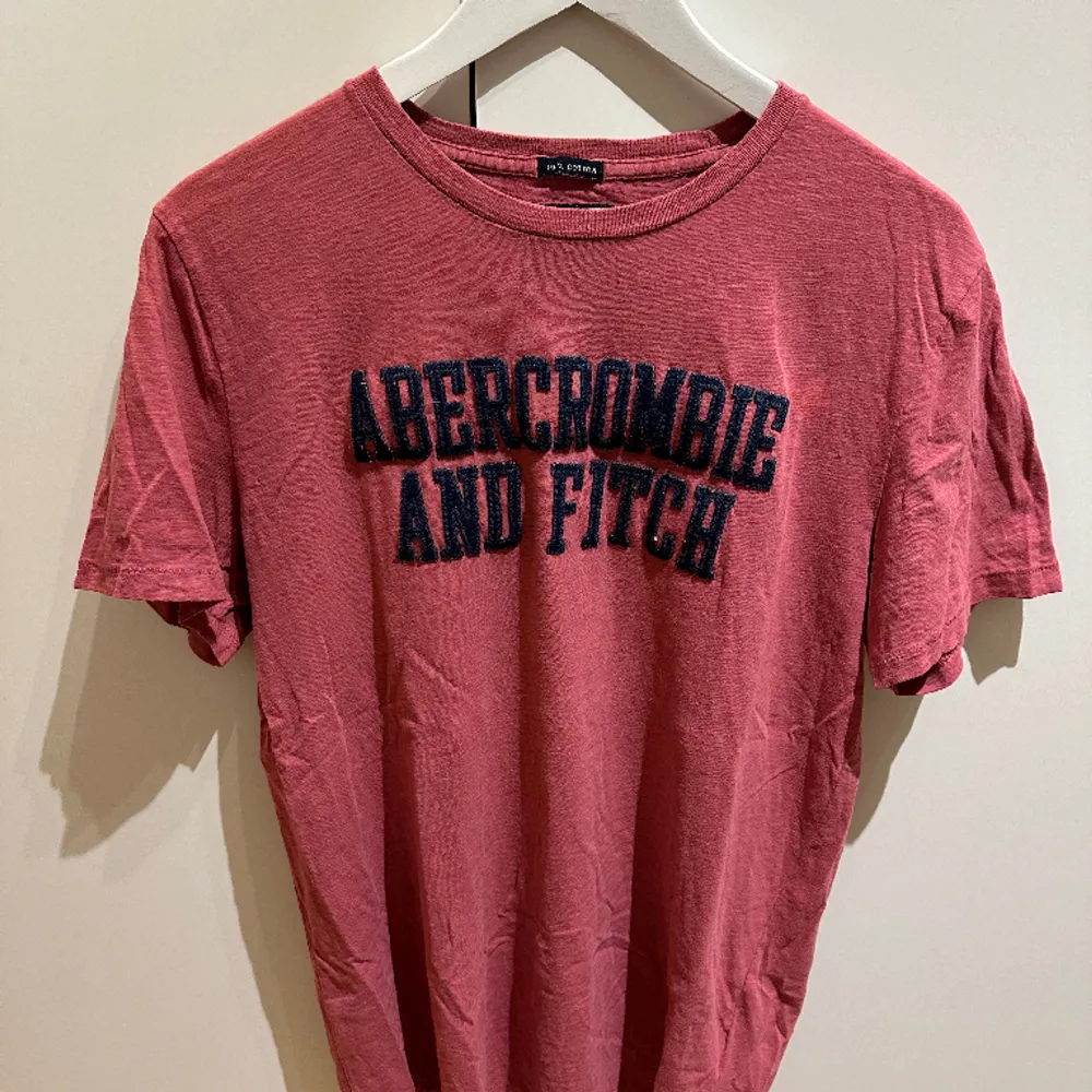 Här presenteras en ljusröd T-shirt från Abercrombie & Fitch. Tillverkad av 100% bomull med en baggy passform. Väldigt bra skick pga dess oanvändning.. T-shirts.