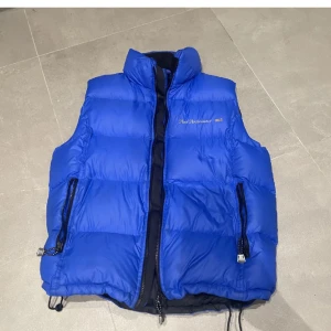 Peak Performance Väst - Retro peak performance väst i färgen blå. Riktigt snygg puffer-väst som sitter otroligt bra. Säljer eftersom jag inte använder längre. Modellen är gammal, så har inte hittat någon liknande. Fick den av min mormor när hon rensade sitt gamla förråd.💙