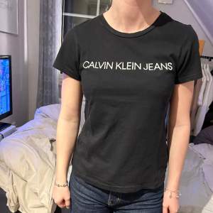 Svart t-shirt med tryck över bröstet från Calvin Klein. Fint skick! Säljer då den är lite liten för mig.