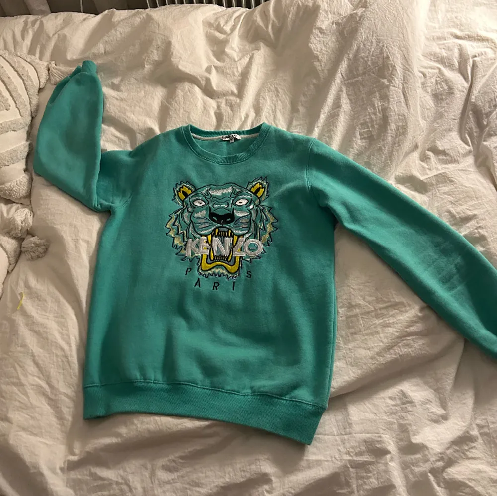 Denna tröja från märket Kenzo Paris i en snygg grön färg. Plagget har använts sparsamt men säljs då jag inte längre använder det. Tröjan är från Kenzos barnkollektion i storlek L men passar personer som bär S/M.. Tröjor & Koftor.