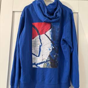 Superfin klarblå hoodie från  Poetic Collective med coolt tryck på ryggen. Mycket fint skick i storlek M. 