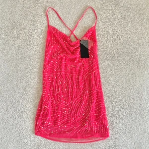 Bershka cerisefärgad festklänning med pärlor - Otroligt snygg klänning från Bershka med paljetter och pärlor. Ny med tags kvar. Några pärlor har lossnat då den är ganska ömtålig men det syns verkligen inte när man bär den.