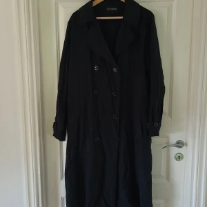 Trenchcoat  - Svartflammig lång kavaj, jacka, trenchcoat. Använd 1 ggn.  Strl L