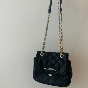 Valentino väska  - Svart perfekt valentino väska, går att ha crossbody samt på axeln. Säljer för den ej används längre. Fint skick liten defekt (se sista bild) nypris 1200kr
