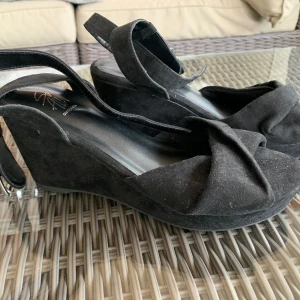 Svarta kilklackar - Svarta kilklackar. Aldrig använda utomhus och är i jättebra skick. På bilden är de bara lite dammiga.