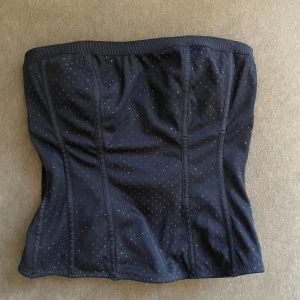 Glittrig korsettopp - Inget märke står skrivet i. Finns två olika knäppen bak och har inbyggd bh i sig. Skulle säga den passar B-C kupa. Subtilt glitter som syns när man rör sig