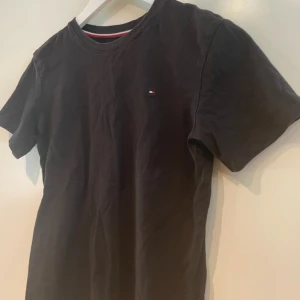 Tommy Hilfiger T-shirt  - En svart t-shirt från Tommy Hilfiger. Inga konstigheter med tröjan bara att den är för liten.