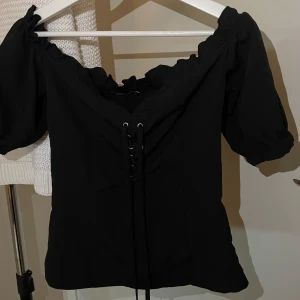 Svart korsett - Svart korsett med snören och dragkedja på sidan.  Storlek 36 