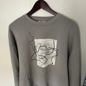 Grå Sweatshirt (Pull&Bear) - Grå sweatshirt ifrån pull&bear med tryck på bröstet. Bra skick och riktigt skön. Säljs för ej användning längre