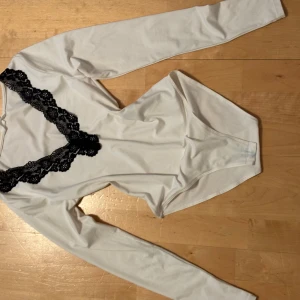 Bodysuit med spets - Lowcut bodysuit med knappar längst ned o svart spets. Säljer för att jag har ny stil 🩵