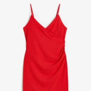 Trikåklänning,XL, mycket fint skick  - En kort klänning i ribbad trikå med djup V-ringning och smala, reglerbara axelband. Klänningen har fastsydd omlott fram med rynkad söm i sidan för en lätt draperad silhuett.