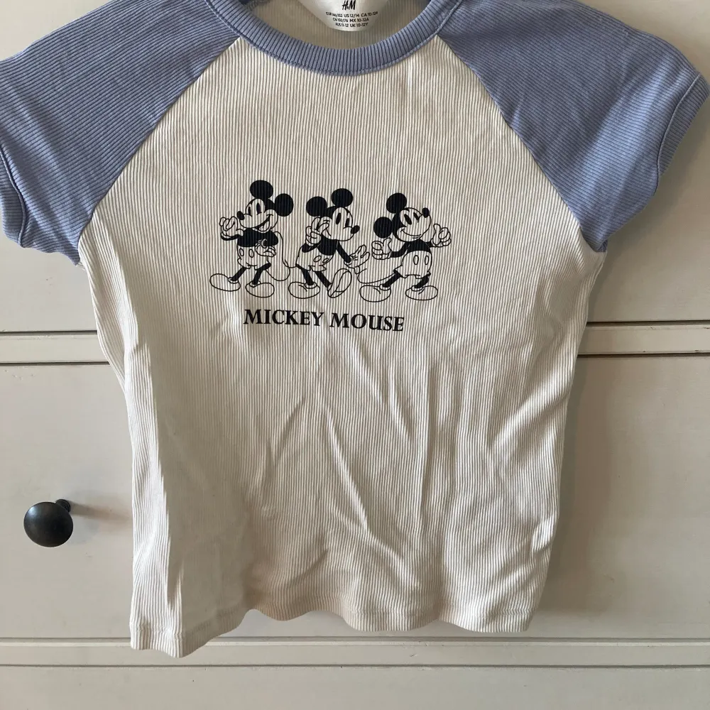 Ribbad T-shirt med Mickey Mouse tryck. Stl 146/152 men liten i storlek. Oanvänd så i nyskick . T-shirts.