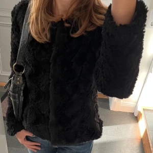 Svart pälsjacka  - Svart jacka från Vero Moda i fuskpäls. Storlek M. Väl använd men ganska fint skick. Säljer flera svarta pälsjackor. Använd gärna köp nu!
