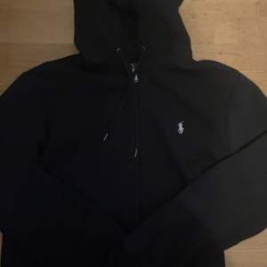 Detta är en hel svart Ralph lauren zip hoodie i skick 8.5/10, använt den ungefär 3-4 gånger så den ser helt ny ut, säljer den för att den har blivit för liten, skriv ifall frågor.