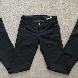 G-star jeans  - Ett par jättesnygga bootcut, g-star jeans köpta second hand som är i väldigt gott skick! Midjemåttet (tvärs över) är 36 cm och innerbenslängden är ungefär 76 cm. Färgen är egentligen mörkblå men ser mer svart ut. Skriv för fler frågor!