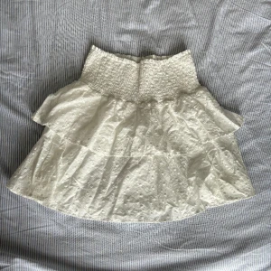 Vit volangkjol💕 - jättesöt vit volangkjol med fina blommor på💗 helt ny, aldrig använt. Super stretchig i midjan! Köpt för 449kr. Skriv om du har några funderingar☺️💕