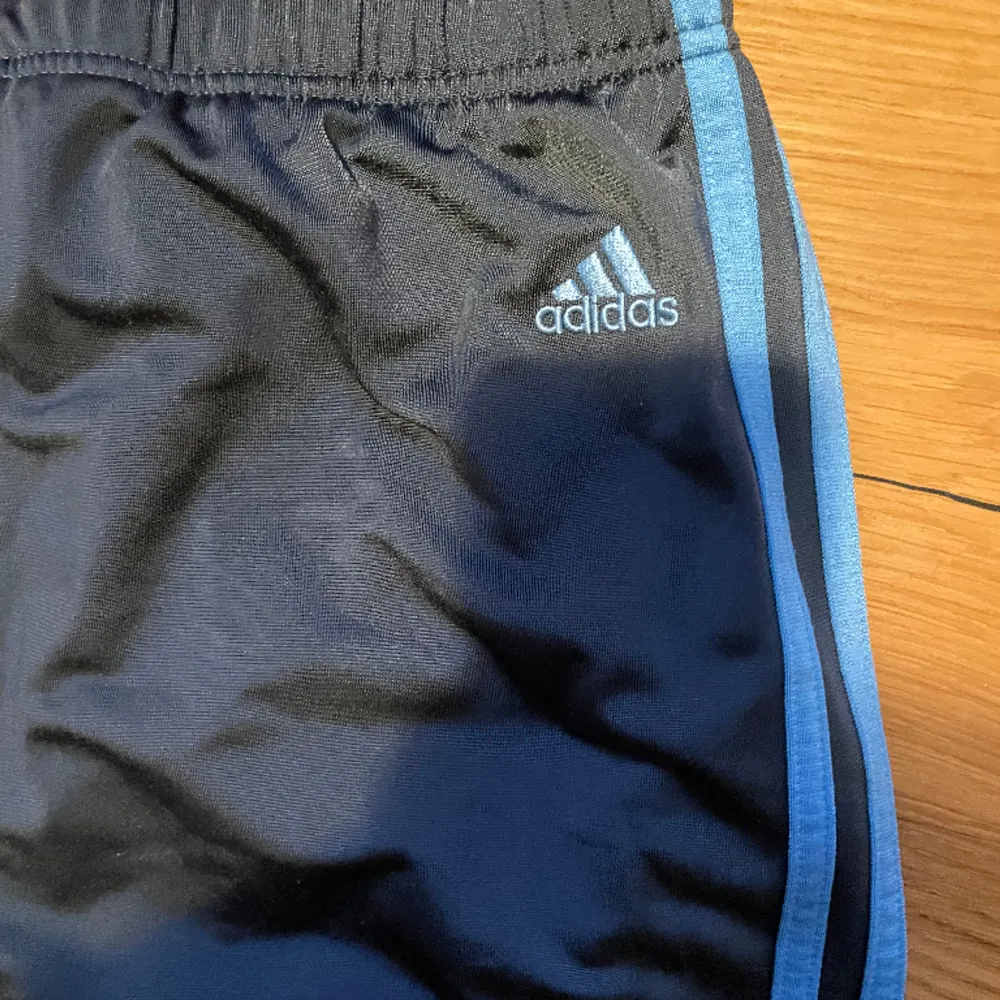 Adidas byxor av ”sportigt” material, kan vikas ned och bli lågmidjade . Inga Defekter, mörkgråa med ljusblå ränder. Jeans & Byxor.