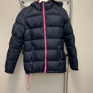 Dunjacka  - Fin dunjacka från tuxer i storlek S.  Den är använd men ändå i fint skick!  Fickor i jackan, på armen och utanpå.  Den är mörkblå med rosa insida