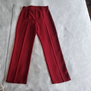 Elegans från 80 talet: röds höga byxor - Den långa,  raka skärningen utstrålar elegans, och den livliga röda färgen är ett modigt uttalande. Det är en del av dräkten med kappa och vest meb kan också köpas separat. 