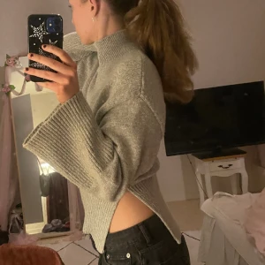 Grå stickad tröja - Supersnygg grå stickad tröja från Gina Tricot med utsvängda armar, hög krage och snygg slits på sidorna. Endast använd en gång💞