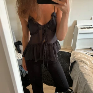 Topp - Svart tunn lite genomskinlig topp i storlek s. Normal passform. Knytning framtill och volanger. Använt några gånger.