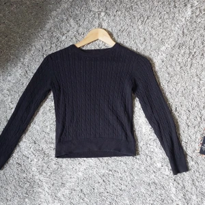 Svart stickad tröja från C'est la vie - Svart stickad tröja med kabelstickat mönster. Storlek 134/140 men passar som en xxs/xs. Mycket fint skick och säljer då den inte kommer till användning