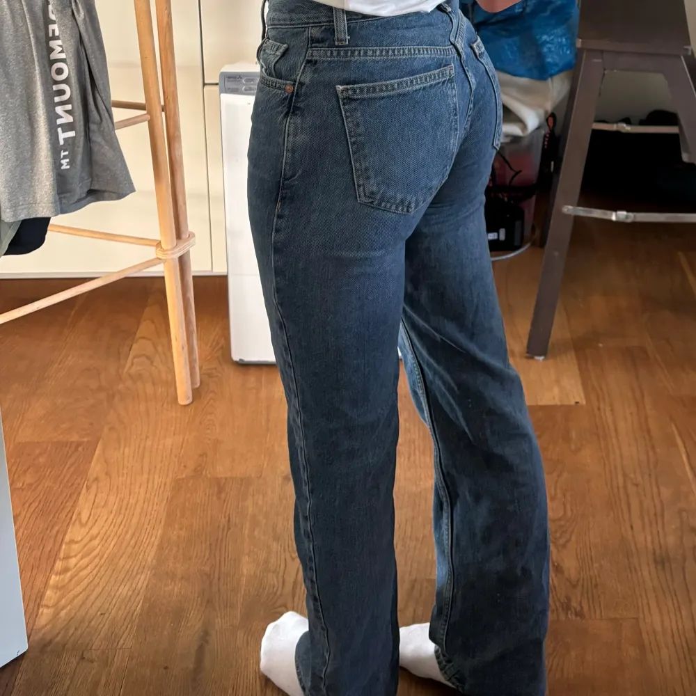 Ett par blå jeansbyxor i storlek 32. Byxorna har en medelhög midja och en rak passform. De har klassiska fem fickor och stängs med dragkedja och knapp.. Jeans & Byxor.