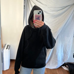 Svart hoodie - En svart hoodie med långa ärmar och en huva. Tröjan är i storlek S och är tillverkad i ett mjukt material.