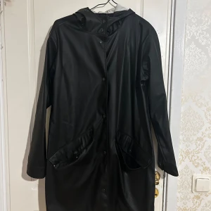 Regnjacka  - Fin och svart regnjacka med huva från Bikbok. Perfekt till det regniga vädret och hösten. Vattentätt och skyddar mot vind. Har 2 normalstora fickorn med knappar. Jackan stängs med knappar. Inga märken på jackan. Pris kan diskuteras.