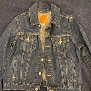 Mörkblå jeansjacka Levis - Säljer denna jeansjacka som jag köpte från Levis för några år sedan men som tyvärr aldrig kommit till användning så den är därmed nästan i nyskick och har inga defekter alls. Perfekt till höst! stl M men jag skulle säga att den passar bättre på xs/s.