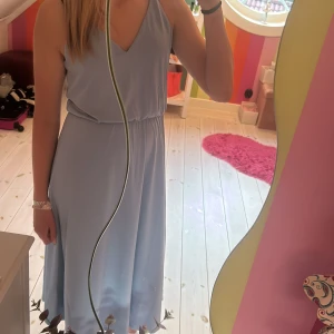 Ljusblå långklänning - Ljusblå långklänning med elastisk söm i midjan från H&M. V-ringad och tunna axelband. Använt max 2 gånger. Nyskick. Säljer då den inte kommer till användning. Bara att skriva vid frågor eller för fler bilder. Pris kan alltid diskuteras.
