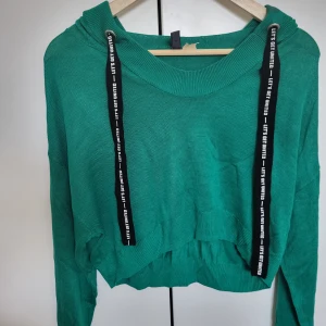 Grön croppad tröja - Grön tröja med långa ärmar och texten "Let's get united" runtom. Tröjan är i en mjukt material och har en avslappnad passform