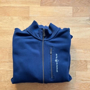 Sail Racing zip tröja. - Blå Sail Racing zip tröja. Tröjan är använd men sparsamt och har inga defekter. Storleken i barnstolek 176 men passar annars xs/s.