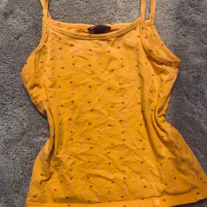 Jättegulligt gul/orange linne med söta blomm detaljer på. Linnet är nästan alldrig använt men är gammalt. Storleken är 146 på lappen. 🤍