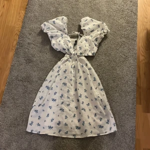 Blåblommigkläning i xs - En blå blommig klänning i xs fina små blommor över hela klänningen den är öppen vid sidorna och har balongarmar den är hyfsat kort!❤️