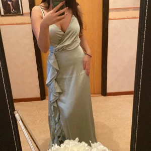 Grön silkes balklänning/bröllopsklänning - Helt ny långklänning (oanvänd) som bara är testad på bilden. Köptes för 2000kr (rabatt). Köptes från en butik. Har en slit på ena sidan med volanger. Slitsen kommer ända upp till mina knän. Är i storlek xs men passar oxå S. Köparen står för frakten ❤️