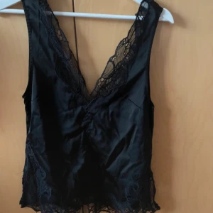 Svart topp - Jättesnygg topp från hm. Knytning baktill och med mönstrat material runt kanterna. Perfekt till fest eller bara i sommar🌟xs i storleken men passar även s