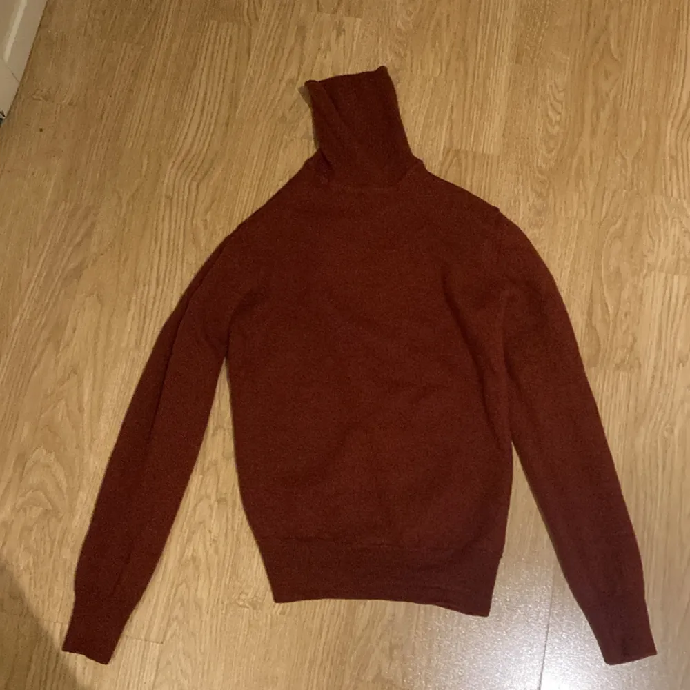 Det är en stickad polo-tröja från J.Lindeberg. Den är vinröd. Tröjan är i storlek S. . Stickat.