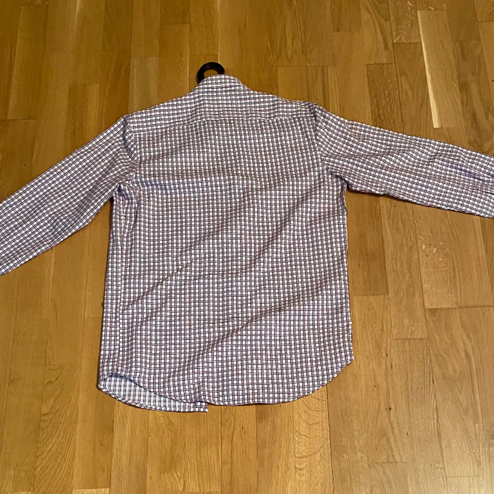 En röd/svart/vit långärmad skjorta i bomull, storlek S. Skjortan har klassisk knappslå och en smal passform - Slim fit. Nästan ny skick, används bara ett par gånger.. Skjortor.