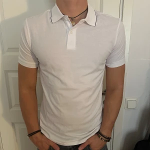 Vit kortärmad pikétröja - Säljer en snygg vit kortärmad slimfit pikétröja. Tröjan har en klassisk krage med knappar och en smal passform som sitter riktigt bra. Helt nytt skick! Storlek S men passar som M. Modellen är 182 cm och väger 75 kg. Pris går att diskuteras!