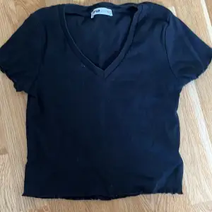 Säljer en svart v-ringad t-shirt från FB Sister i storlek XS. T-shirten är kortärmad och har en croppad stil. Lite använd men fortfarande i bra skick.