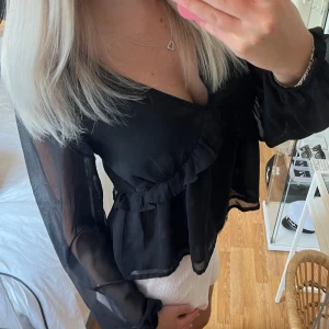 Volangblus i chiffong - Blus i chiffong . Färgen svart. Volang med vringad urringning. Chiffong material. Jättefint skick, som ny. Från BikBok. Storlek XS. 💗
