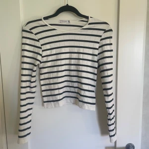 Randig långärmad tröja från Brandy Melville - Säljer en superfin randig tröja från Stradivarius . Den är vit med svarta ränder och har en tight passform. Tröjan är långärmad och ribbad, vilket gör den både bekväm och stilren. Nyskick!