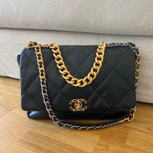 Svart quiltad axelväska med guldkedja - Säljer en snygg svart quiltad axelväska, Chanel liknande. nyskick