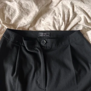 Svarta kostymbyxor  - Säljer ett par svarta kostymbyxor från Bershka. De är midwaist och har en knapp och dragkedja framtill. De är i mycket bra skick och har en elegant och tidlös design.