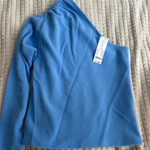 Tröja från Gina tricot   - Blå one shoulder tröja med prislappen kvar.  Köpt för 300 kr. Storlek S. 