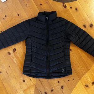 Svart dunjacka - ridning - En svart dunjacka från Jacson. Mycket bra skick, knappt använd. Funkar lika bra till vardags som i stallet, som till ridning. Storlek S